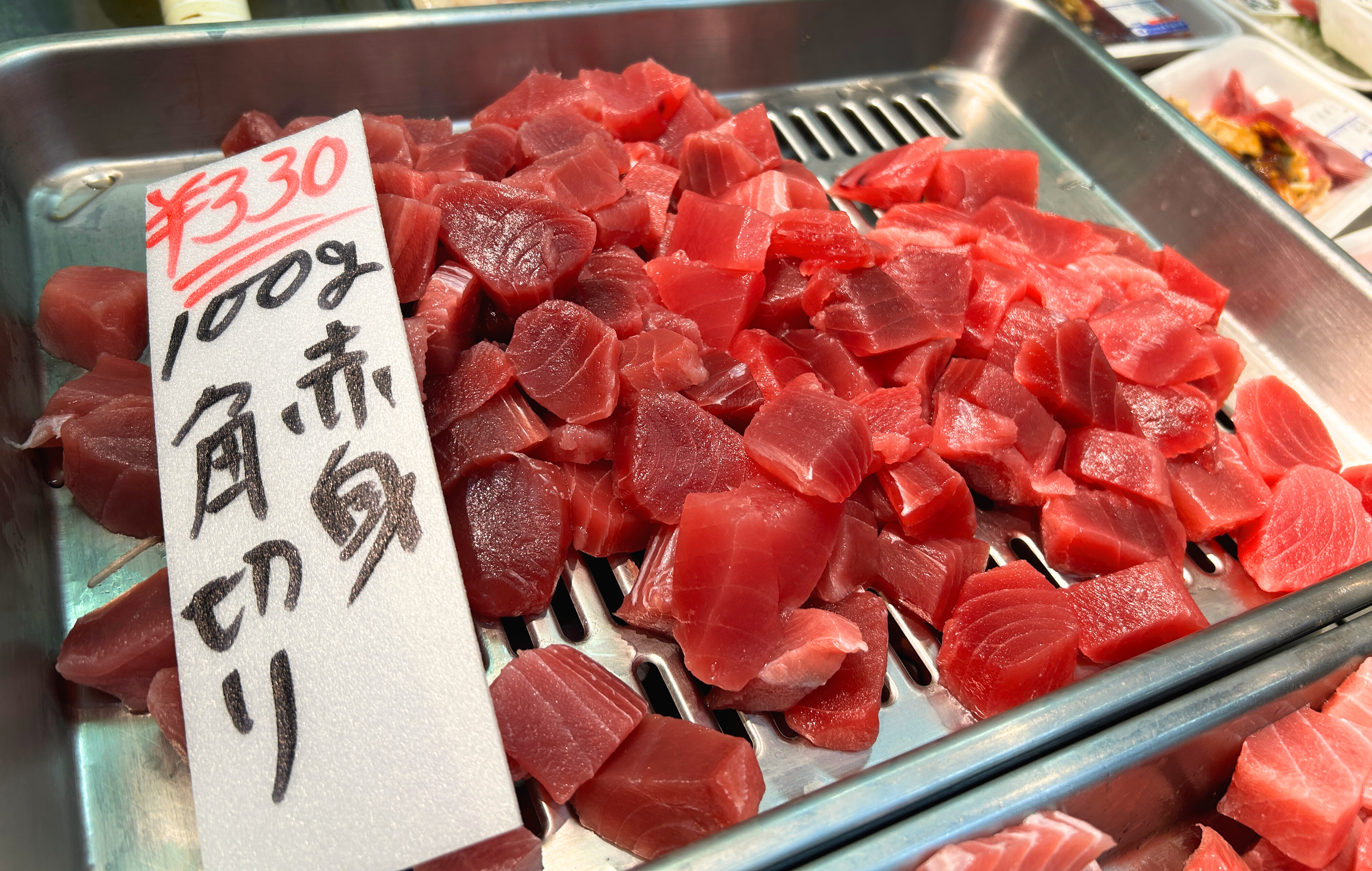 "¡Bienvenido!" Una voz animada saluda al comerciante de una tienda de atún en una calle comercial de larga tradición.