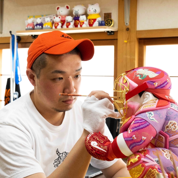 Una muñeca Hakata con un motivo de atrapasueños, representada en colores vivos.