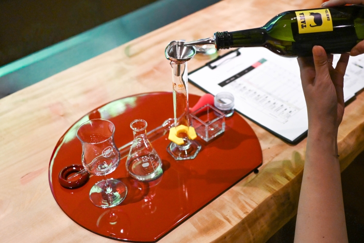 El proceso de mezclar de 2 a 4 tipos de sake utilizando vasos de precipitados y probetas graduadas.