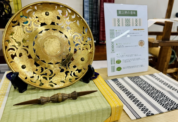 Los utensilios budistas representados en el diseño forman un patrón de homenaje: abajo a la izquierda: dokko (un tipo de vajra), arriba a la izquierda: hanazara (un tipo de plato floral).