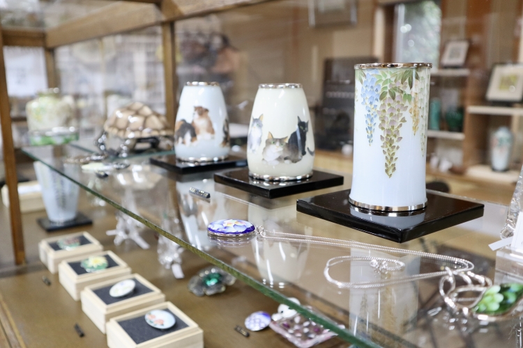 En el escaparate de la tienda se exhibe una variedad de objetos de esmalte cloisonné.