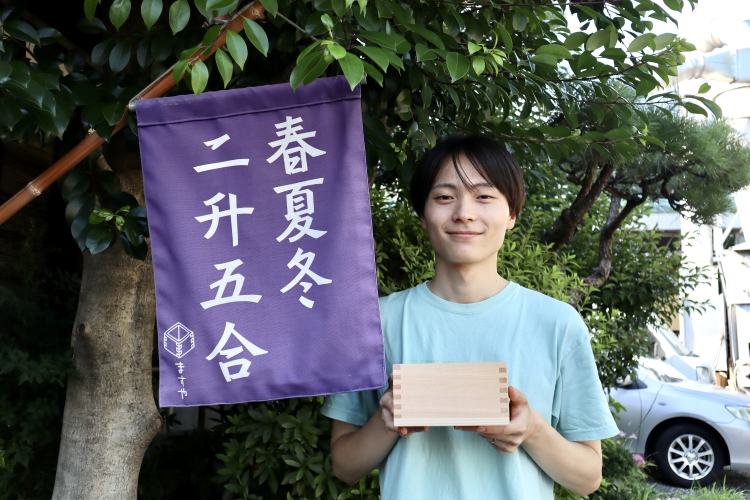 Hayato Oguchi, del departamento de ventas. La bandera representa "negocios (sin otoño), crecimiento (dos tazas medidoras) y prosperidad (media taza medidora)".